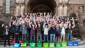 Foto von allen Beteiligten der Projektwoche von 2017. Alle stehen vor Stufen vor einem Gebäude und werfen die Arme in die Luft. Vor ihnen stehen BASF Taschen in unterschiedlichen Farben.