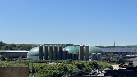 Foto: Landwirtschaftliche Biogasanlage mit Kuhstall, Traktor, Fermenter, Speichersystemen