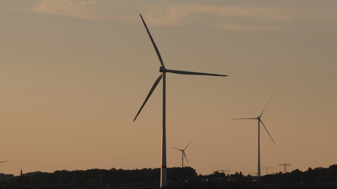 Foto: Windräder vor einer Landschaft im Sonnenuntergang 