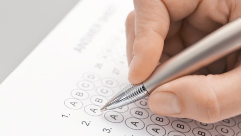 photograph of a hand holding a pen and filling in a multiple-choice questionnaire