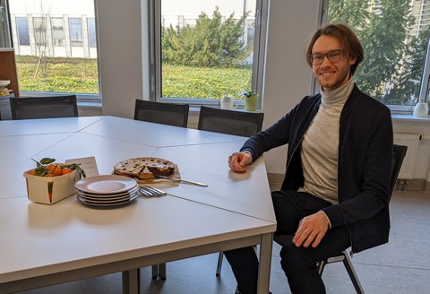 Stipendiat am Tisch auf dem Kuchen, Teller und ein Obstkörbchen stehen