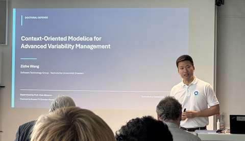 Zizhe Wang hält seinen Vortrag. Im Hintergrund wird seine Präsentation an die Wand projiziert.