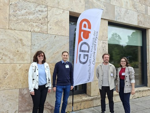 Professorin Manuela Niethammer, Jannik Amon sowie Darius Mertlik und Carmen Helbig stehen gemeinsam vor dem Veranstaltungsgebäude der Jahrestagung der Gesellschaft für Didaktik der Chemie und Physik.