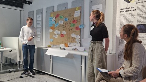 Kollegiat Jannik Amon (links) und Kollegiatin Marie Walstab (rechts) präsentieren den Teilnehmenden die Dikussionsergebnisse