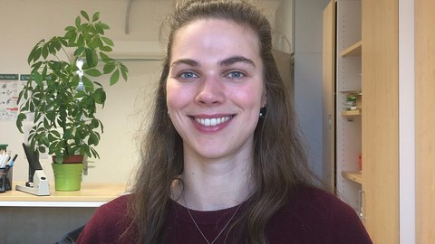  Kollegiatin Sophie Jacobs steht lächelnd in einem Büro der Professur