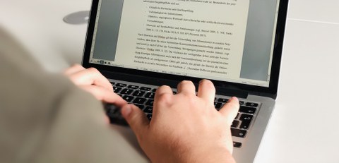 Jemand schreibt einen Text an einem Laptop.
