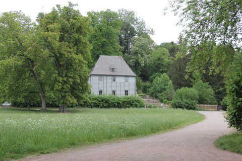 Foto von Goethes Gartenhaus im Ilmpark in Weimar. Dieses ist umgeben von Gehölzen.