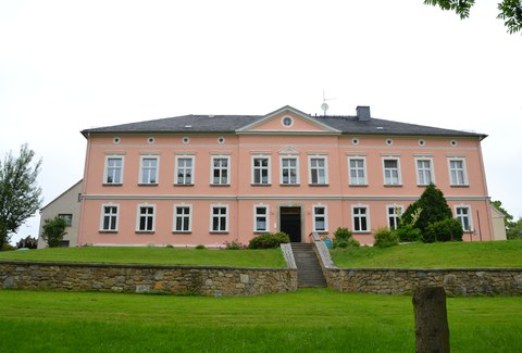 Foto zeigt das Pfarrhaus in Crostwitz, welches über eine Treppe über die Wiesenfläche erreichbar ist. 