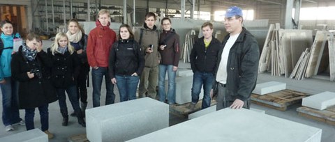 Foto einer Gruppe von Studierenden im Betonwerk Grafe versammelt um einen Betonblock.