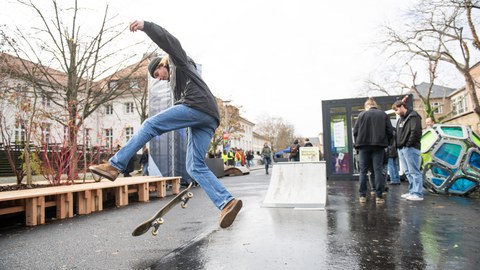 Person mit Skateboard vor Holzdeck