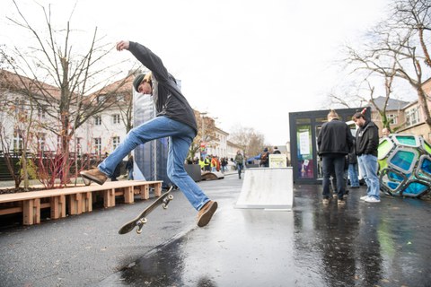 Person mit Skateboard vor Holzdeck