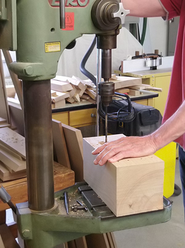 Bild eines Holzblockes in dem Löcher gebohrt werden