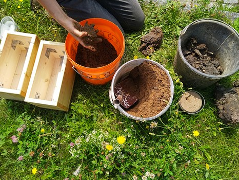 Bild von mehreren Eimern, gefüllt mit Mörtel und Sand.