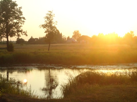 Foto mit Sonnenuntergang hinter einem Teich und einem ukrainischen Dorf