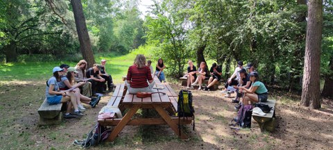 Gruppe Studierender sitzt an einem Picknickplatz im Wald