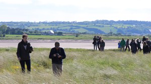 Foto von Studierenden auf einer Exkursion in Irland, welche über eine grüne Wiese gehen.