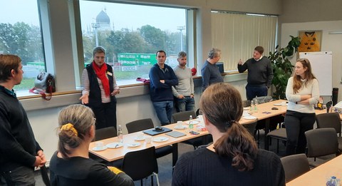 Die Teilnehmer des Workshop stehen in Kleingruppen im Raum und diskutieren miteinander.