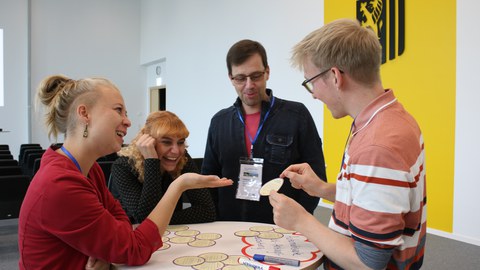 Teilnehmende diskutieren in einer Workshop-Session lachend über die Beiträge.