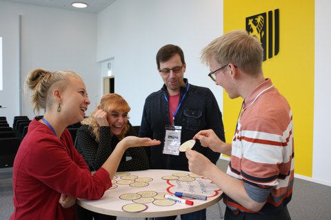 Teilnehmende diskutieren in einer Workshop-Session lachend über die Beiträge.