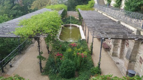 Foto zeigt einen Terrassengarten. Die abgebildete Terrasse besteht aus zwei Pergolen, welche durch einen Wasserspiel getrennt sind.