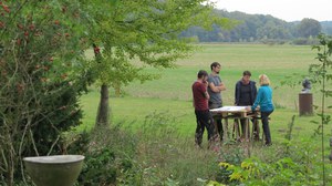 Foto von vier Personen auf einer Wiese, die an einem Tisch arbeiten