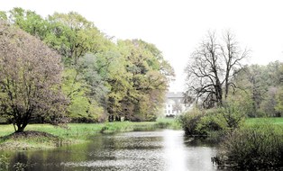 Foto eines Landschaftspark mit Fluss und Herrenhaus dahinter