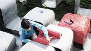 Foto einer Studierenden die Betonmöbel in rote Folie einpackt