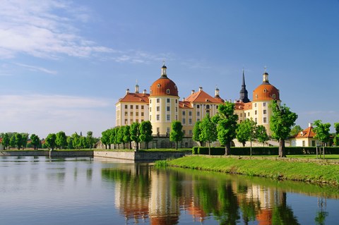 Das Foto zeigt das Schloss Moritzburg bei Dresden im Sommer. Im Vordergrund befindet sich ein See.