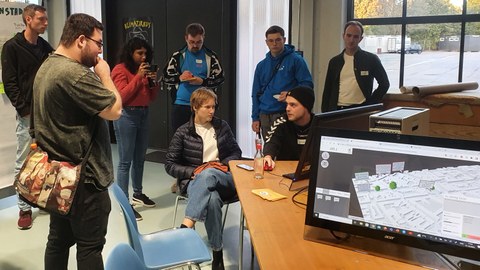 Das U_CODE-Team diskutiert mit Jugendlichen an den Bildschirmen über Stadtplanung