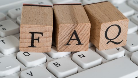 Das Foto zeigt drei Holzwürfel auf einer Tastatur. Auf den Holzwürfeln sind die Buchstaben FAQ abgebildet.