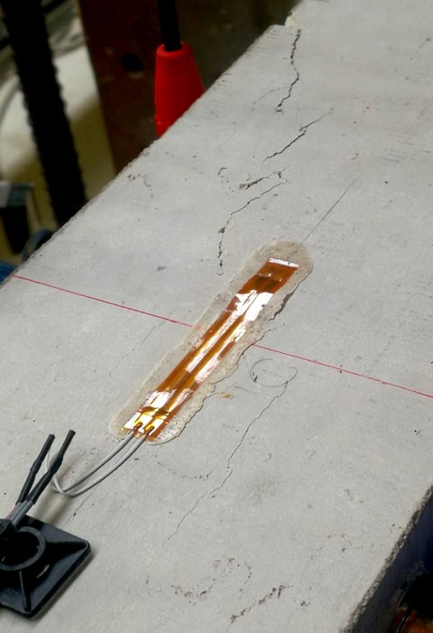 Strain gauge glued at the cracked concrete compression zone after the fatigue test