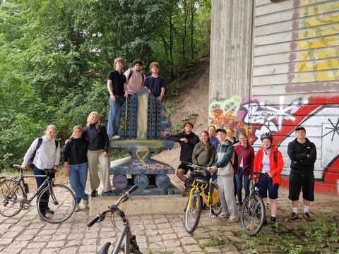 Gruppe von Studierenden und Lehrenden mit Fahrrädern unter einer Brücke