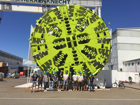 Gruppenfoto vor einer Tunnelbohrmaschine des Herstellers "Herrenknecht" mit einem Durchmesser von fast dem Sechsfachen der Länge eines Menschen 