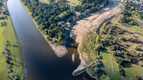 Luftaufnahme von Dresden an der Elbe im Spätsommer mit ausgeprägten Trockenheitsspuren: Niedrigwasser im Elbarm, ausgetrocknete Auenwiesen und herbstliche Laubfärbung entlang des Ufers.