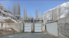 View of the two weir fields in the centre of the picture, on the right is the bypass entrance and a vertical trash rack, snow-covered mountains in the background