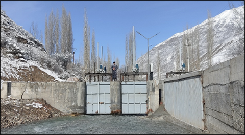 View of the two weir fields in the centre of the picture, on the right is the bypass entrance and a vertical trash rack, snow-covered mountains in the background