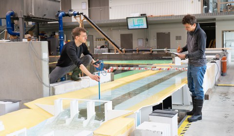 Man erkennt eine manuelle Fließgeschwindigkeitsmessung im Labir in der Nähe der sogenannten Rossweidschleuse. Eine Person misst und eine weitere Person dokumentiert auf einem Schreibblock.