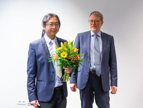 Professor Kaliske übergibt Blumen an den Doktoranden