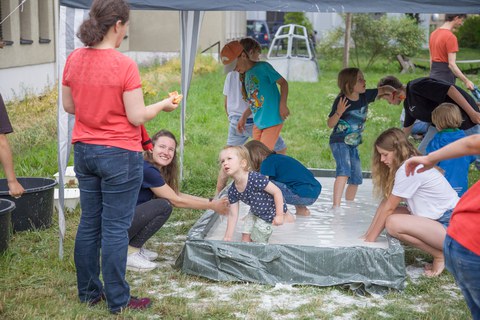 Ein Bad im Stärkewasser, viele Kinder stehen in der Wanne