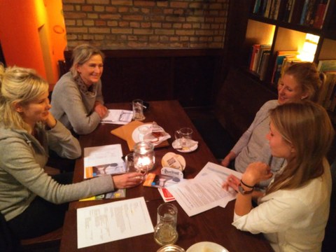vier Frauen sitzen an einem Tisch und unterhalten sich freundlich