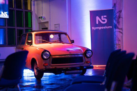 Roter Trabi neben N5 Symposium Aufsteller