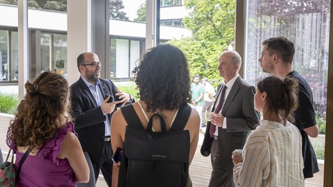 Gemischte Gruppe in lebhafter Diskussion neben einem offenen Fenster