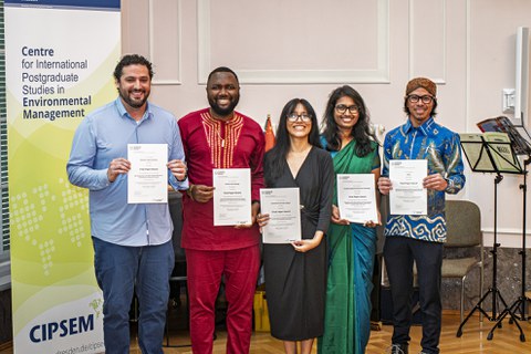 Five EM48 course participants stand side by side, smiling and holding their certificates during the closing ceremony in Dresden.