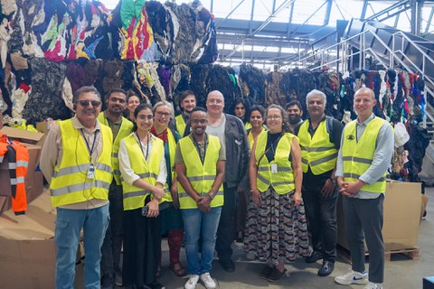 Group in front of a huge pile of textiles sorted for recycling.