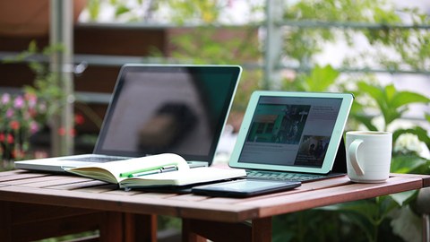 Laptop, Tablet und Buch auf Tisch