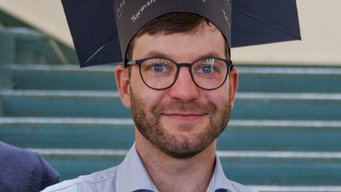 Herr Georgi lächelt mit Hut auf dem Kopf in die Kamera