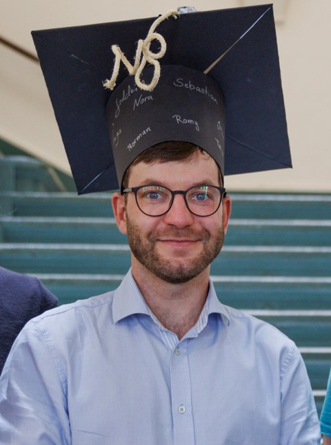 Herr Georgi lächelt mit Hut auf dem Kopf in die Kamera