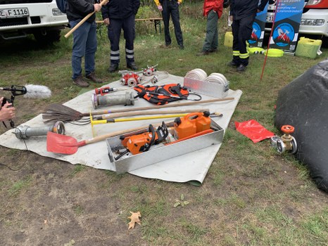 Various tools used for fighting wildfires (from front: chainsaw, shovel, McLeod, valves, pitchfork, swatter, water backpack, smaller hose, water divider)