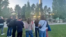 Gruppe von Menschen auf einer Wiese, die einem Vortrag zuhören