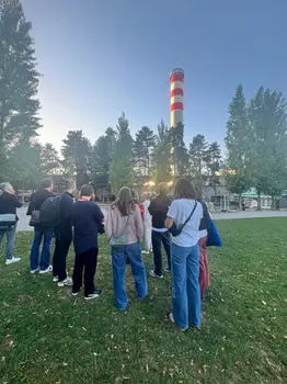Gruppe von Menschen auf einer Wiese, die einem Vortrag zuhören